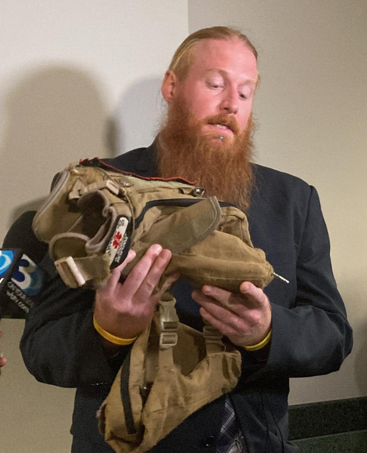 Joshua Rohrer holds a vest belonging to his late service dog, Sunshine Rae. The vest still features a prong from a taser that a police officer shot at Sunshine.