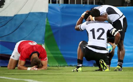 2016 Rio Olympics - Rugby - Men's Gold Medal Match - Fiji v Great Britain - Deodoro Stadium - Rio de Janeiro, Brazil - 11/08/2016. Vatemo Ravouvou (FIJ) of Fiji celebrates with a teammate as Tom Mitchell (GBR) of Great Britain reacts. REUTERS/Alessandro Bianchi