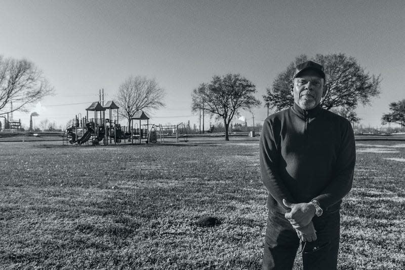 John Beard poses at Carver Terrace Park in Port Arthur, with refinery smokestacks visible less than half a mile away.