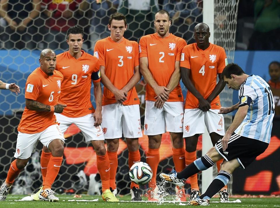 Argentina's Lionel Messi (R) takes a free kick near Netherlands' players (L-2nd R) Nigel de Jong, Robin van Persie, Stefan de Vrij, Ron Vlaar and Bruno Martins Indi during their 2014 World Cup semi-finals at the Corinthians arena in Sao Paulo July 9, 2014. REUTERS/Dylan Martinez (BRAZIL - Tags: SOCCER SPORT WORLD CUP)