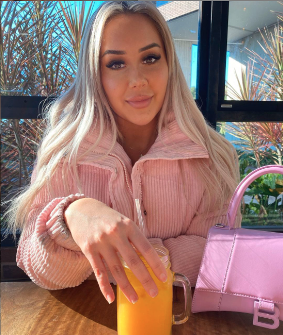 Cathy Evans from MAFS in a pink coat holding a glass of orange juice