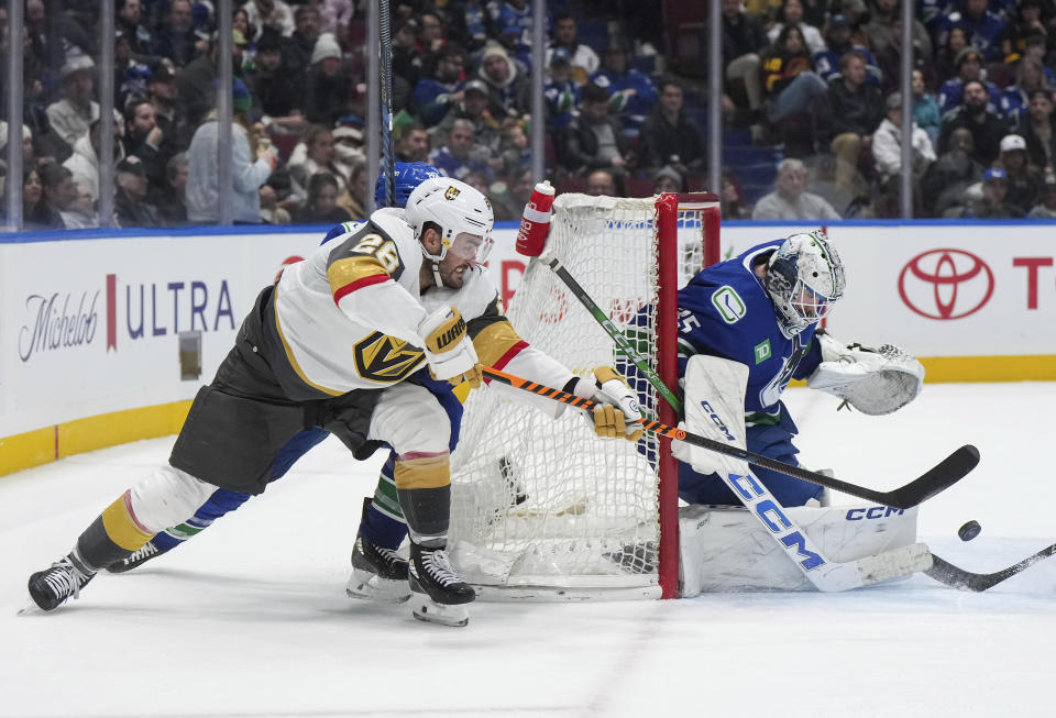 Vegas Golden Knights' William Carrier, left, passes the puck next to Vancouver Canucks goalie Thatcher Demko during the second period of an NHL hockey game Thursday, Nov 30, 2023, in Vancouver, British Columbia. (Darryl Dyck/The Canadian Press via AP)