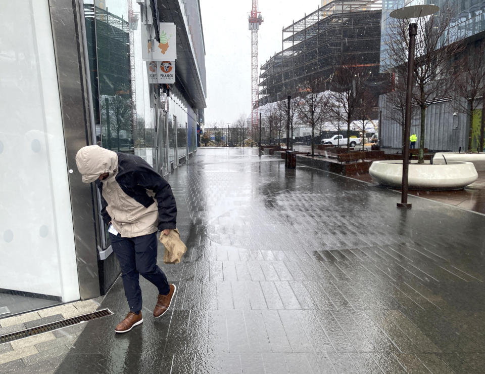 A person braces against the wind as a wintry mix of snow and rain falls in Boston, Tuesday, March 14, 2023. A winter storm is dumping heavy, wet snow in parts of the Northeast, causing tens of thousands of power outages, widespread school closings, dangerous road conditions and a plane to slide off a taxiway. The storm's path Tuesday included parts of New England, upstate New York, northeastern Pennsylvania and northern New Jersey. (AP Photo/Michael Casey)