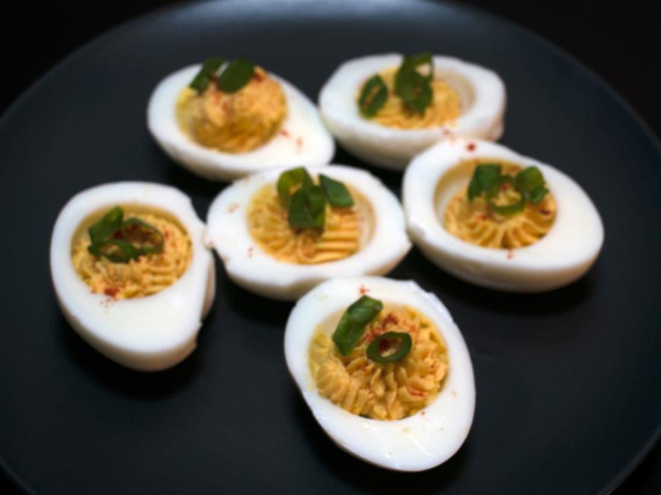 Six deviled eggs with paprika.