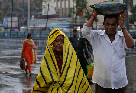 Commuters shelter from the rains as they cross a road in Kolkata, India, May 3, 2019. REUTERS/Rupak De Chowdhuri