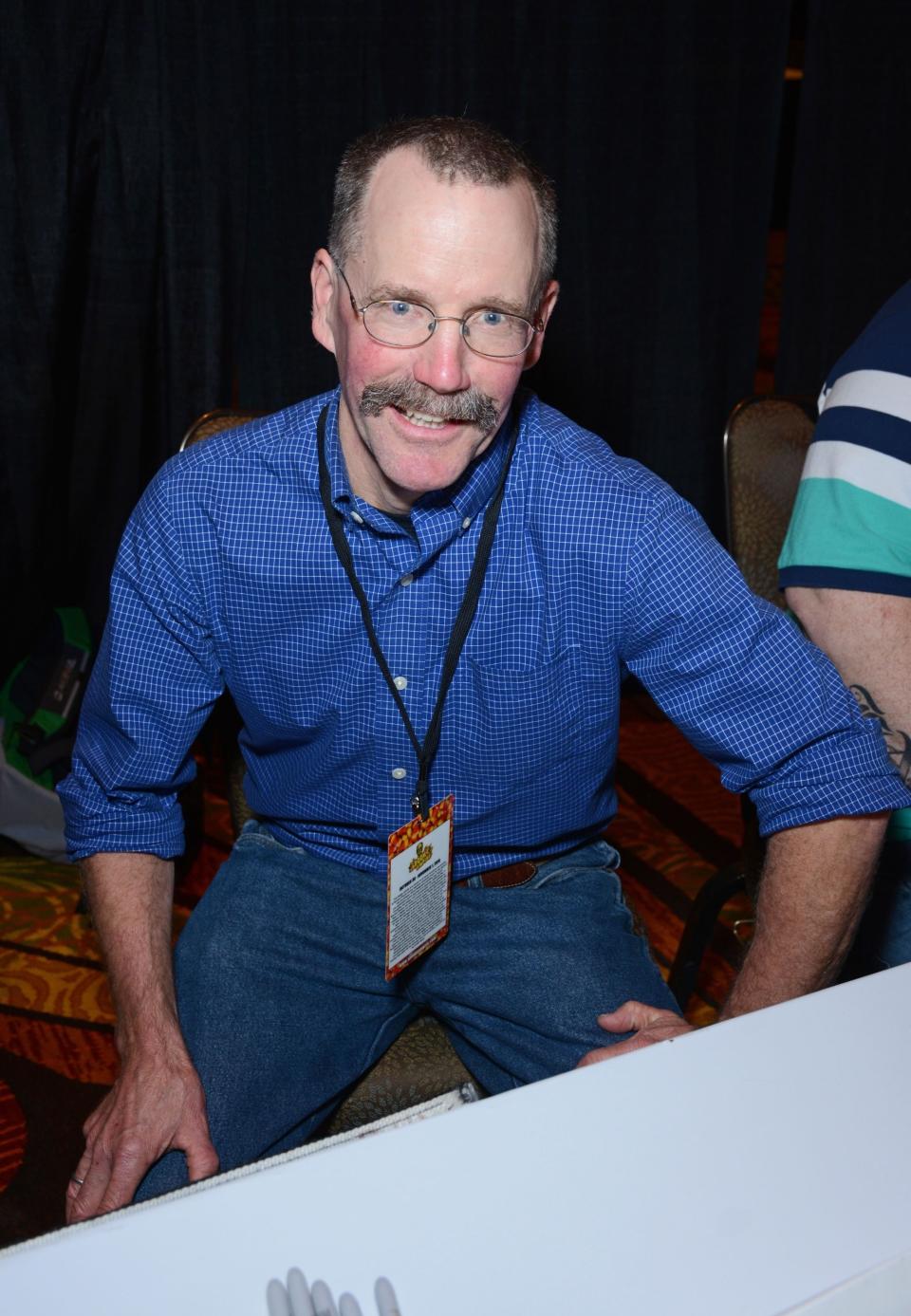 Smiling man in glasses and jeans sitting down