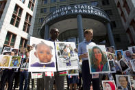 Fathers Paul Njoroge, left, and Michael Stumo, hold the pictures of the family members they lost in the plane crash during a vigil on the six-month anniversary of the crash of a Boeing 737 Max 8, killing 157 people, in Ethiopia on March 10, which has resulted in the grounding hundreds of the planes worldwide, outside of the Department of Transportation, Tuesday, Sept. 10, 2019 in Washington. (AP Photo/Jose Luis Magana)