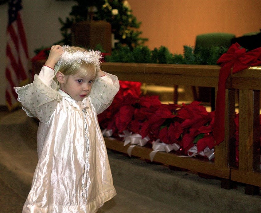 Riley Goolishian, 2, fixes her halo as she goes to the front of the church during the Children's Christmas Eve Service at the First United Methodist Church in Portland on Dec. 24, 2001.