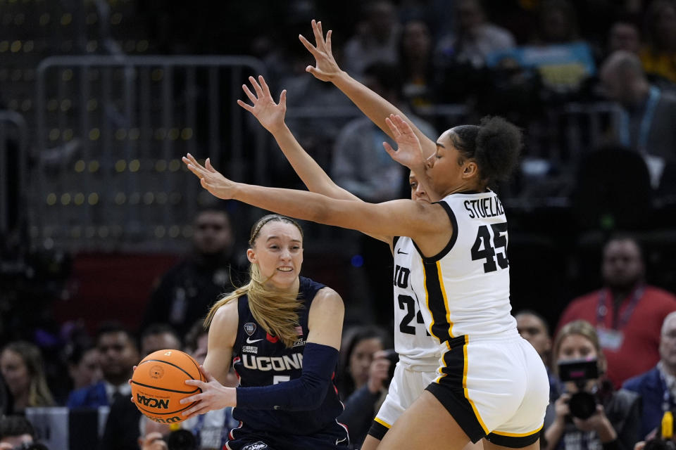 UConn guard Paige Bueckers (5) passes around Iowa forward Hannah Stuelke (45) during the first half of a Final Four college basketball game in the women's NCAA Tournament, Friday, April 5, 2024, in Cleveland. (AP Photo/Carolyn Kaster)