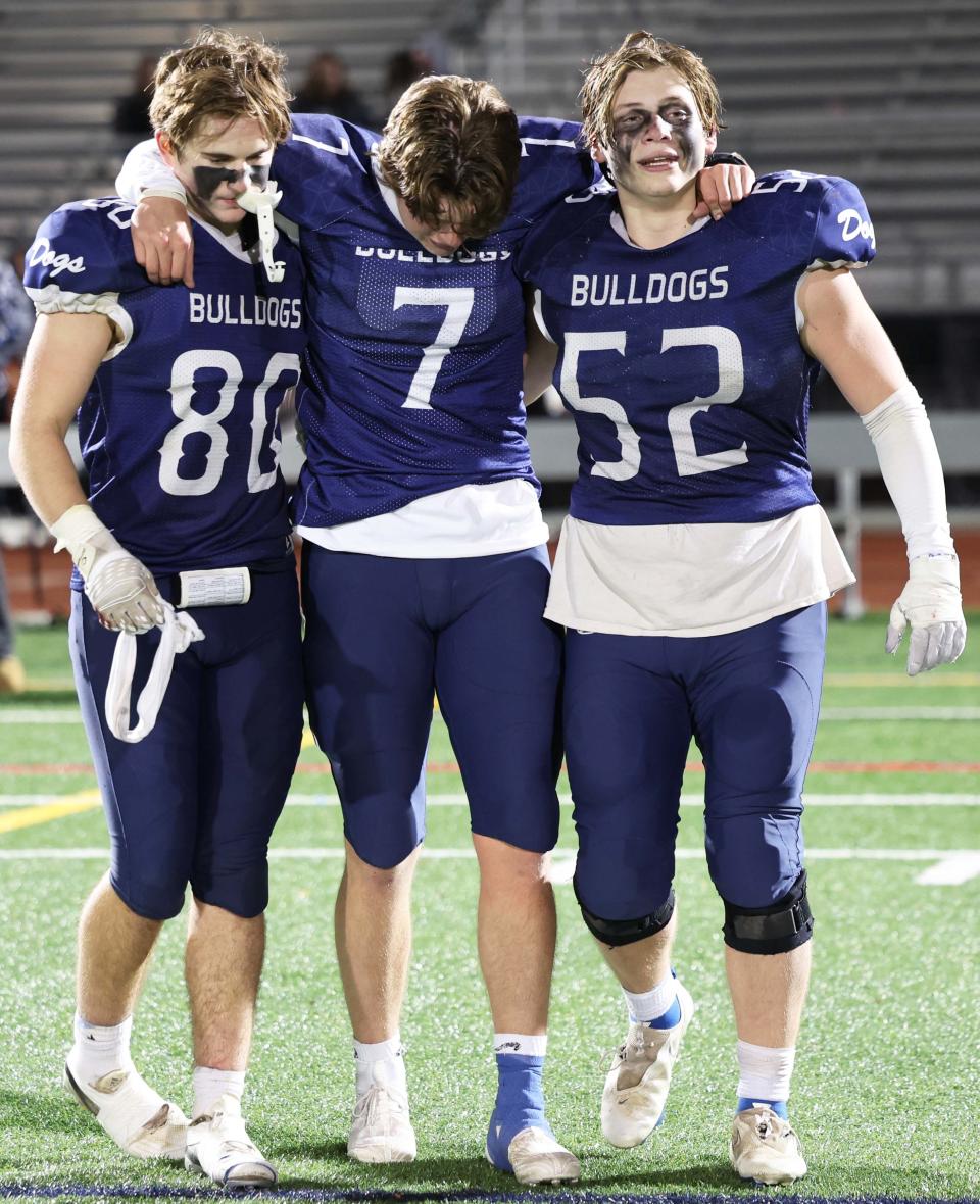 Rockland quarterback Michael Moriarty, center, is helped onto the field by Logan Rogers, left, Leary Costa, at the conclusion of their game versus St. Mary's at Walpole High School on Friday, Nov. 18, 2022.   