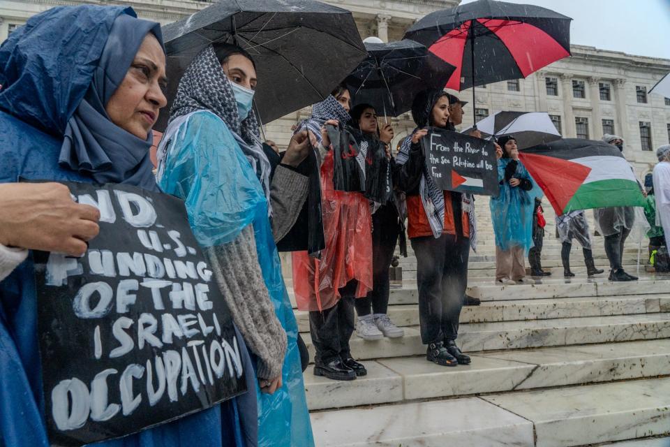 Demonstrators at Saturday's State House rally hold signs expressing support for Palestinians affected by the conflict between Israel and Hamas.