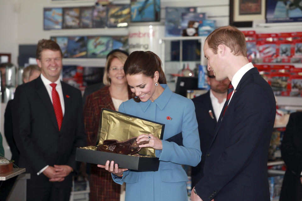 Britain's Prince William, right, and his wife Kate, the Duchess of Cambridge, center, look at a gift given to them for their son Prince George as they tour the Omaka Aviation Heritage Centre in Blenheim, New Zealand, Thursday, April 10, 2014. (AP Photo/Tim Cuff, Pool)