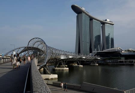 People walk past the Marina Bay Sands hotel in Singapore April 10, 2017. REUTERS/Edgar Su/Files