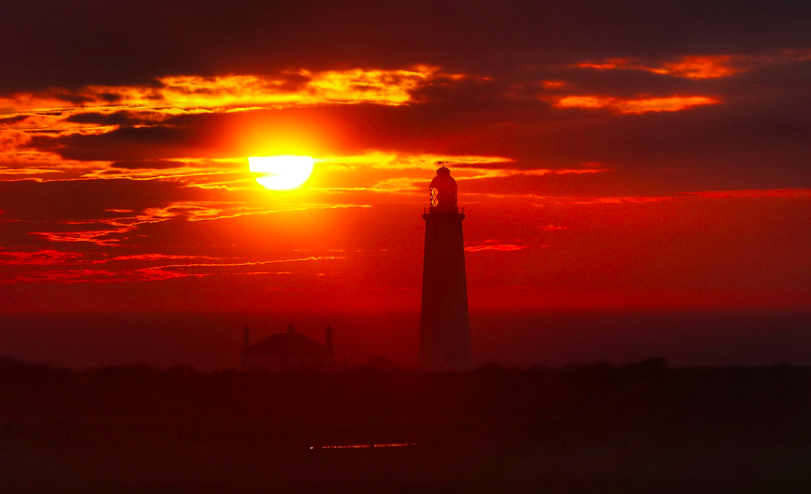 <em>The sun rises at St Mary’s Lighthouse in Whitley Bay, Northumberland, on what is set to be the hottest day of the year so far (PA)</em>