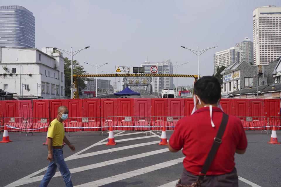 Residents wearing masks pass by barriers used to form a security checkpoint in the Haizhu district in Guangzhou in southern China's Guangdong province, Friday, Nov. 11, 2022. As the country reported 10,729 new COVID cases on Friday, more than 5 million people were under lockdown in the southern manufacturing hub Guangzhou and the western megacity Chongqing. (AP Photo)