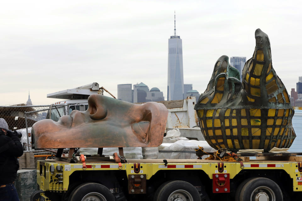 The original torch of the Statue of Liberty, and a replica of her face, rest on a hydraulically stabilized transporter, Thursday, Nov. 15, 2018 in New York. The torch, which was removed in 1984 and replaced by a replica, was being moved into what will become its permanent home at a new museum on Liberty Island. New York's One World Trade Center is visible, background center. (AP Photo/Richard Drew)