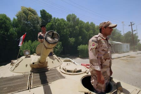 Iraqi soldiers sit on a tank at the entry of Zubair oilfield after a rocket struck the site of residential and operations headquarters of several oil companies in Basra