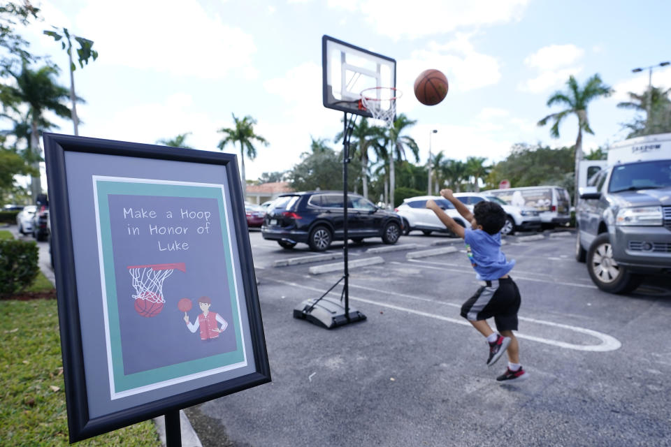 A young boy plays basketball, Tuesday, Feb. 14, 2023, at a ceremony in Coral Springs, Fla., honoring the lives of the 17 students and staff of Marjory Stoneman Douglas High School that were killed on Valentine's Day, 2018. Victim Luke Hoyer was passionate about basketball. (AP Photo/Wilfredo Lee)