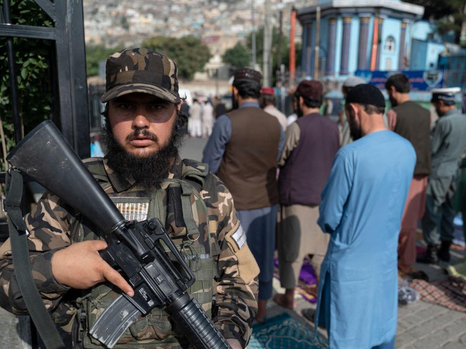 A Taliban fighter stands guard as Afghan Muslim devotees offer their Eid al-Adha prayers at Shah-e-Do Shamshira mosque in Kabul on July 9, 2022.