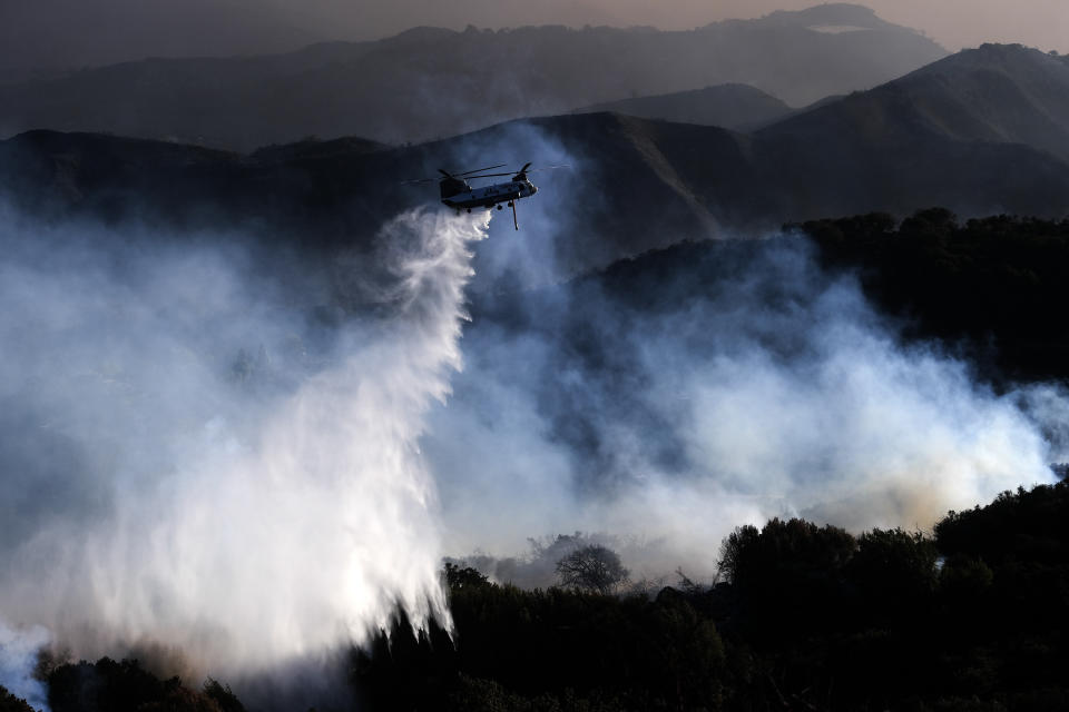 A helicopter drops water on a wildfire Wednesday, Oct. 13, 2021, in Goleta, Calif. (AP Photo/Ringo H.W. Chiu)