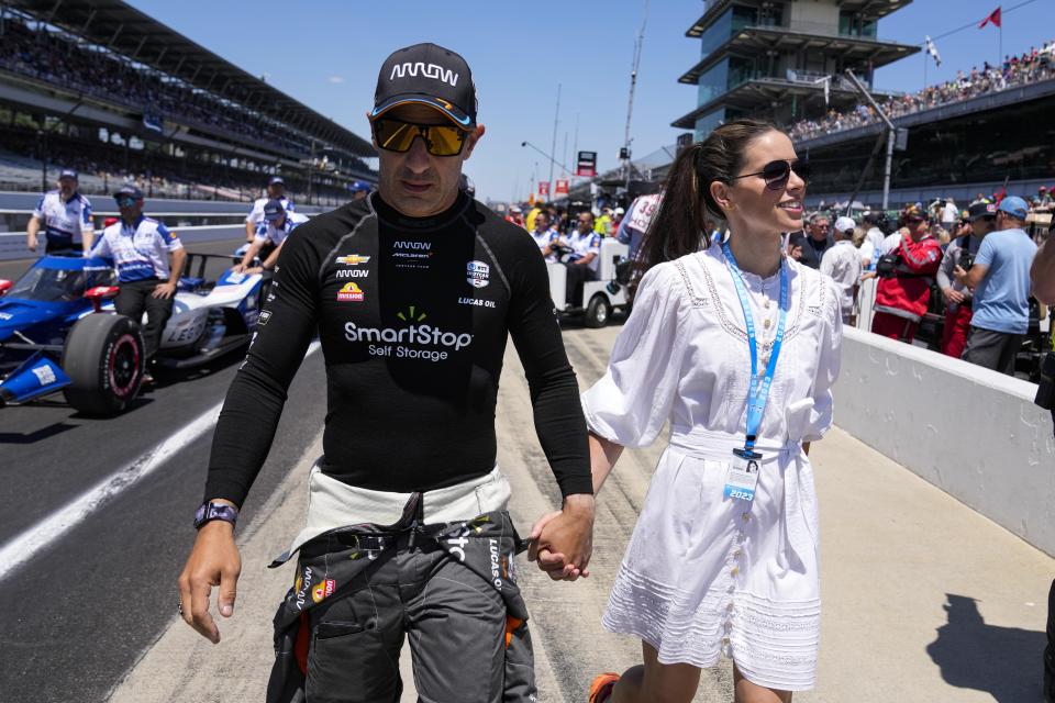 Tony Kanaan, of Brazil, left, walks with his wife Lauren Bohlander before the start of qualifications for the Indianapolis 500 auto race at Indianapolis Motor Speedway in Indianapolis, Sunday, May 21, 2023. (AP Photo/Michael Conroy)
