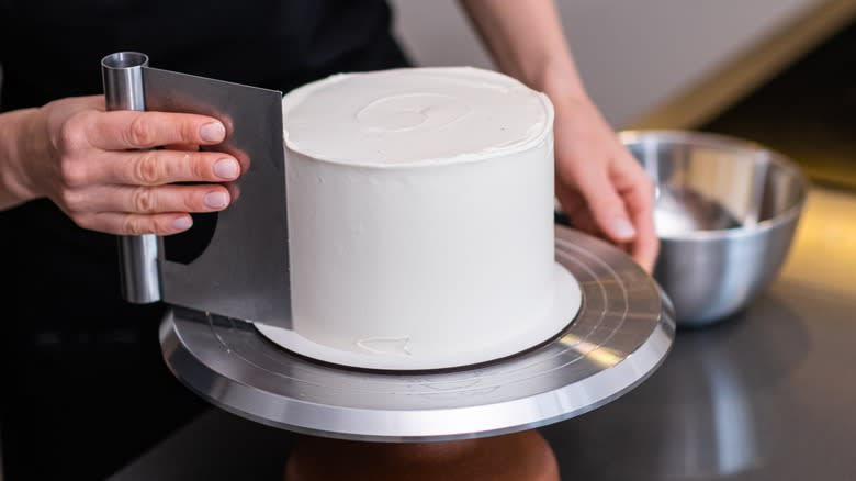 Person scraping icing on a cake