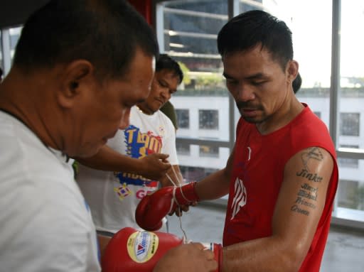 Philippine boxing legend Manny Pacquiao unlaces his gloves after training at a gym in Manila ahead of his world welterweight boxing championship bout against Argentina's Lucas Matthysse in July
