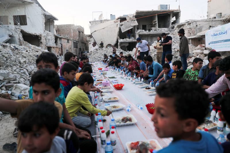 Children eat their Iftar meal provided by a group of volunteers in a damaged neighbourhood, amid fear for the coronavirus disease (COVID-19) outbreak, in Atarib