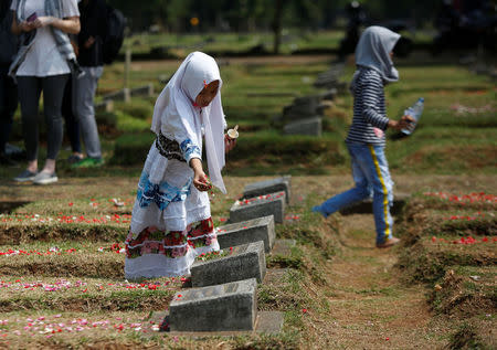 A girl places flowers on the graves of some of the victims who died during the political turmoil of 1998 during a 20th anniversary commemoration at Pondok Ranggon mass grave in Jakarta, Indonesia, May 13, 2018. Picture taken May 13, 2018. REUTERS/Willy Kurniawan