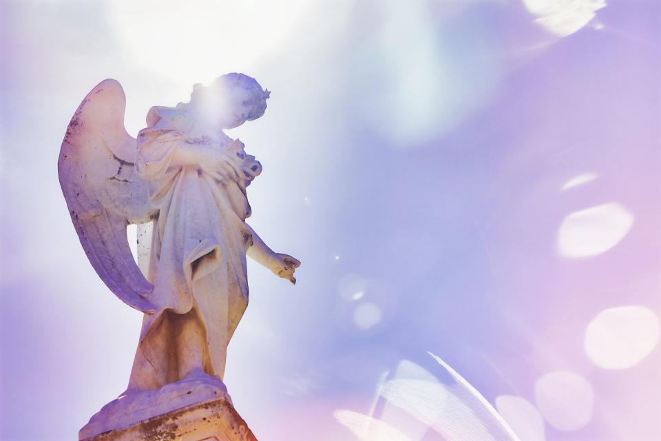 angel looking down on a graves at a cemetery