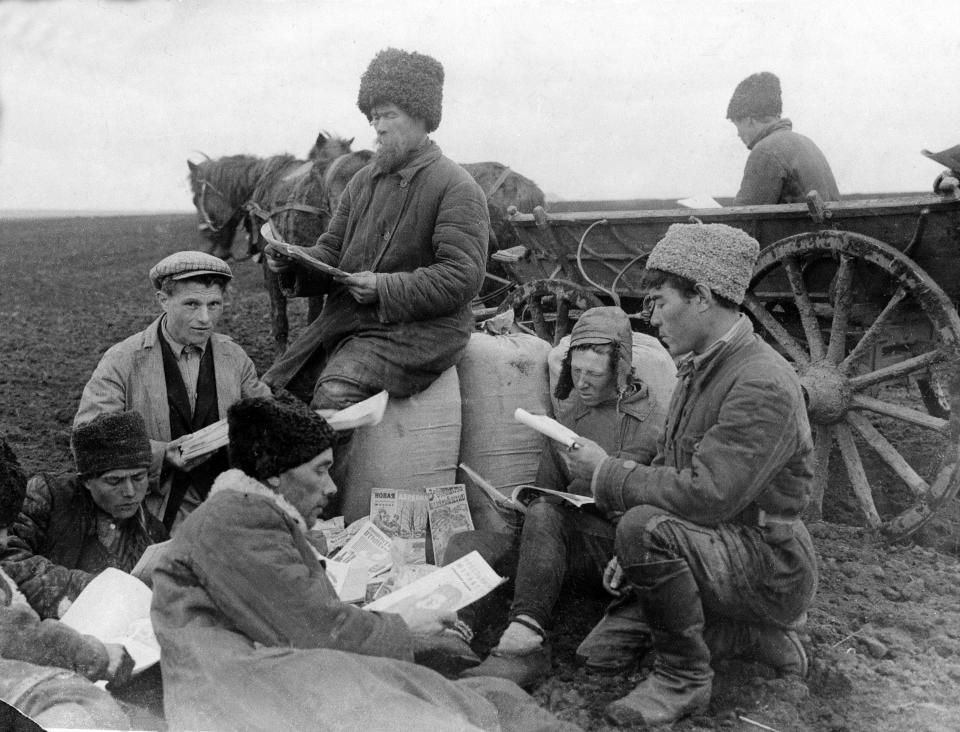 FILE - A group of peasants, who work in the fields of their collective farm, read magazines and newspapers during rest hour, at an unknown location in the Soviet Union, on May 28, 1930. Stalin implemented collectivization, in which private landholdings were incorporated into state and collective farms. (AP Photo/File)