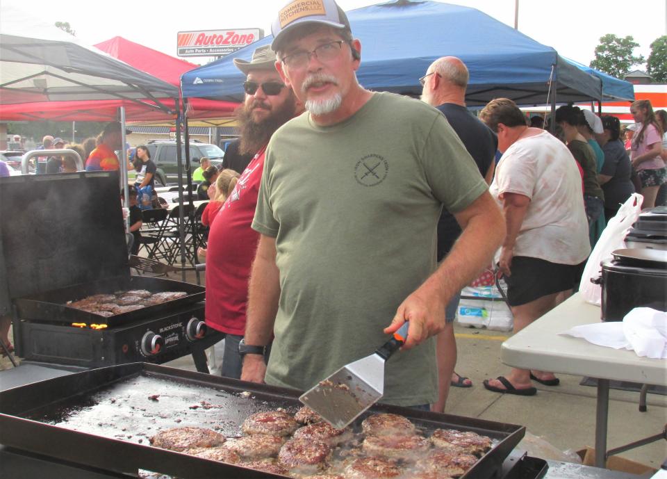 Dave Schlabach and Kevin Lint were busy on the grill Sunday night serving up hamburgers to visiting utility workers stuck in the area away from their families on Father's Day.