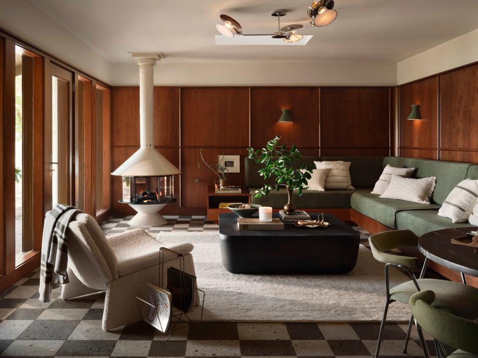 A sitting room with a couch built into the wall, wood paneling, and a black coffee table.