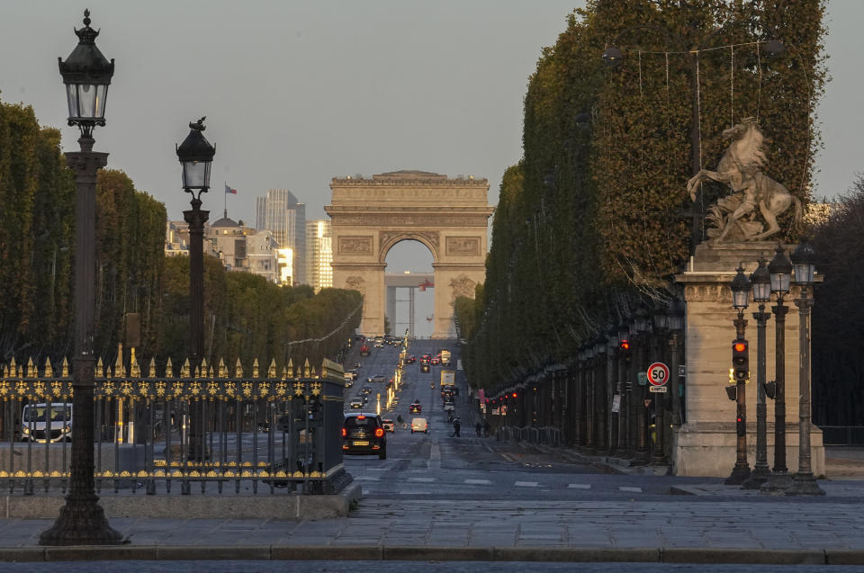 Cars make their way up the Champs-Elysees avenue with the Arc de Triomphe in background, during sunrise Tuesday, Nov, 1, 2022. Paris is on track to host millions of visitors and successfully stage 32 sporting events next year when the 2024 Olympics open on July 26. That's a welcome return to business as usual for the first post-pandemic Olympics. (AP Photo/Michel Euler)