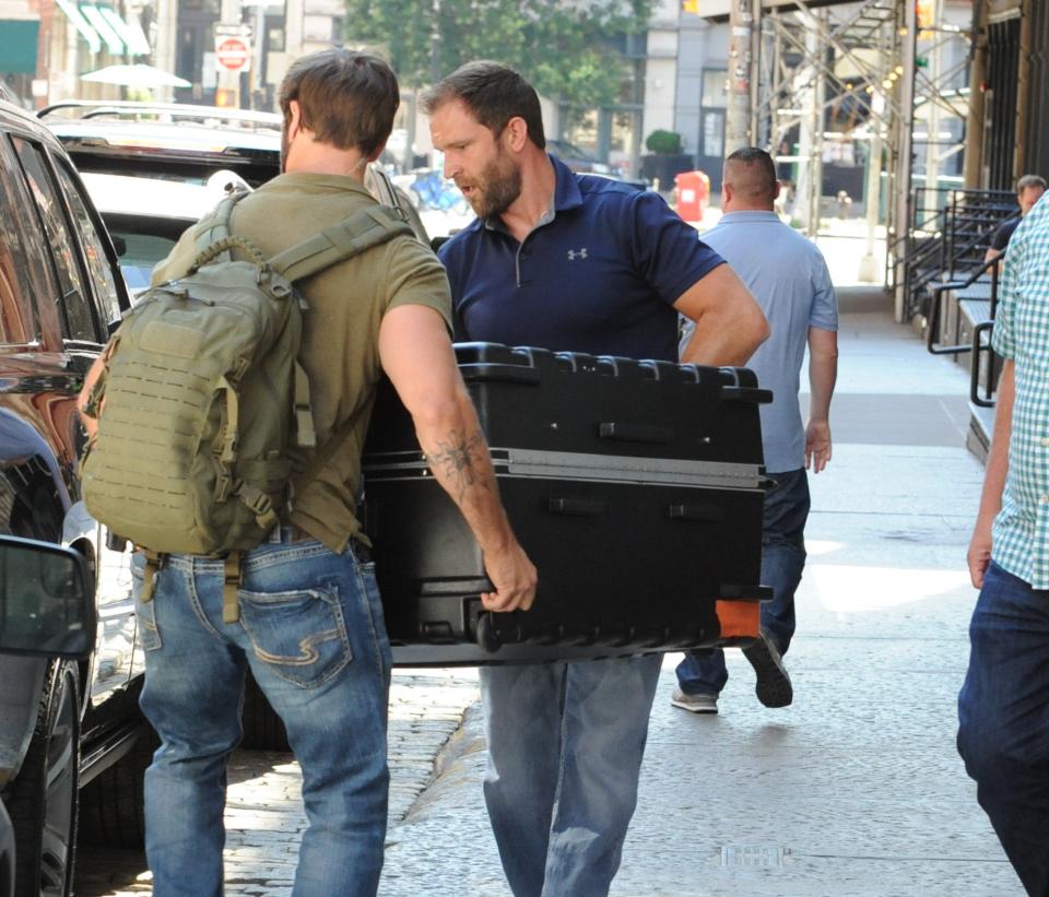 Two men carrying an oversized suitcase to a car