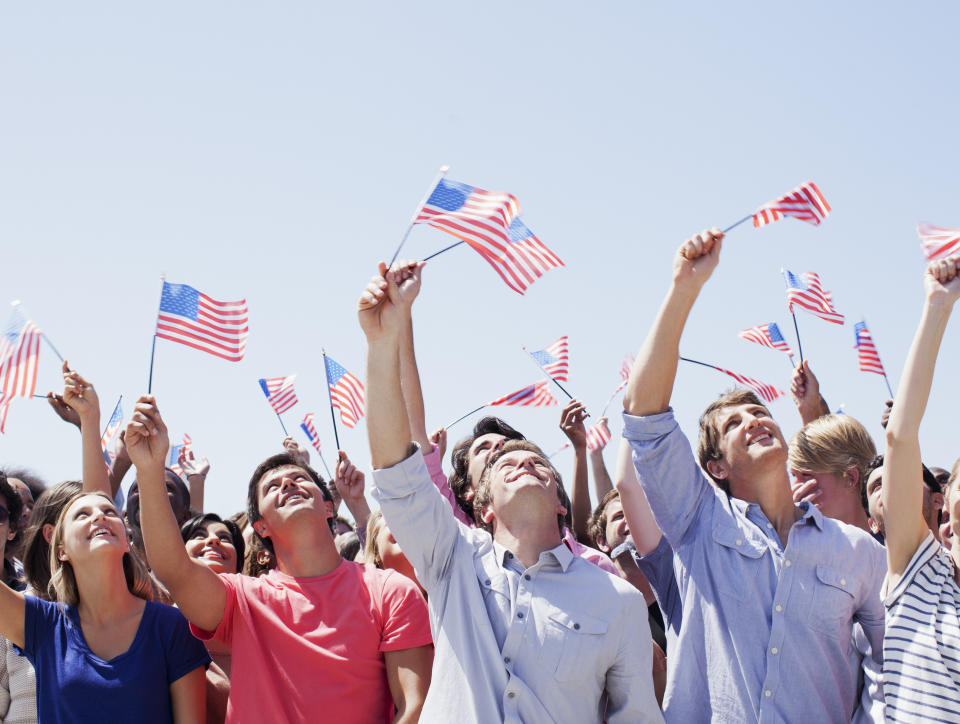 Group of people waving small American flags in celebration