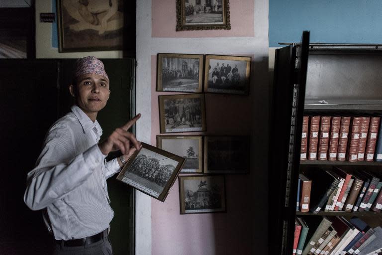 An employee looks at framed photographs alongside damaged book shelves at the Kaiser Library in Kathmandu on May 7, 2015