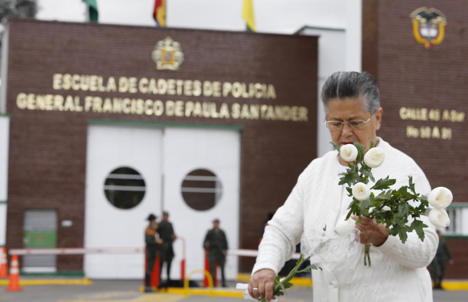 Una mujer coloca flores en un altar improvisado afuera de la Escuela de Cadetes de Policía General Francisco de Paula Santander, un día después de que un coche bomba explotara en esa academia, en Bogotá, Colombia, el viernes 18 de enero del 2019. (AP Foto/John Wilson Vizcaino)