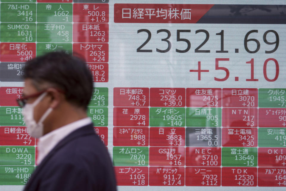 A man walks past an electronic stock board showing Japan's Nikkei 225 index at a securities firm in Tokyo Monday, Oct. 26, 2020. Asian shares were little changed in muted trading Monday amid widespread uncertainty over what the U.S. presidential election will portend for markets and economic policy.(AP Photo/Eugene Hoshiko)