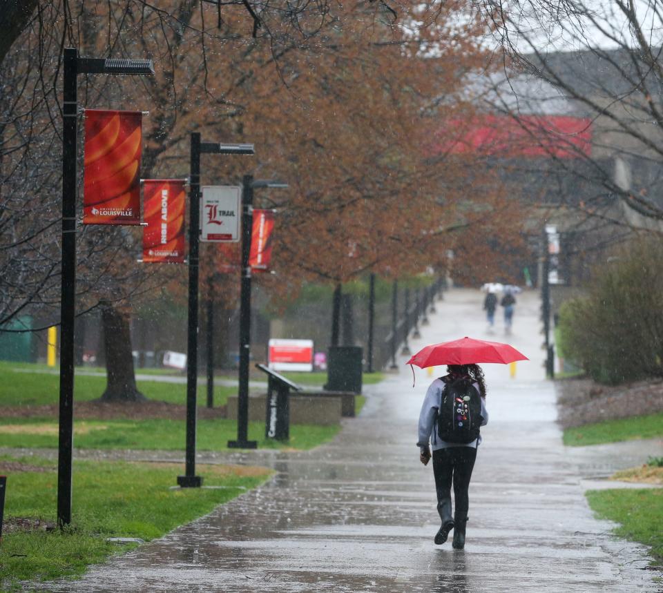 A UofL student makes their way through the heart of the campus on Friday, March 24, 2023, as several rounds of rain moved through Louisville.