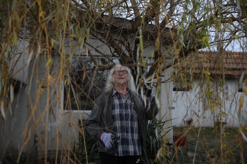 Waldemar Hackstaetter trims a tree outside his house in the village of Sirakovo