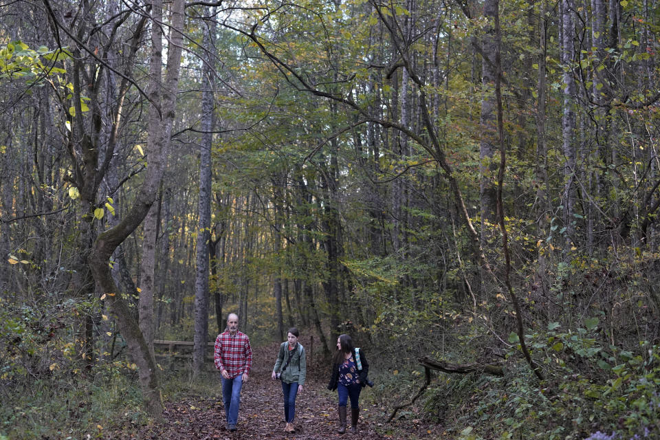 Olivia Chaffin, center, walks in the woods with her parents, Doug, left, and Kim Chaffin, as Olivia works on a Girl Scout photography merit badge in Jonesborough, Tenn., on Sunday, Nov. 1, 2020. Olivia, who stopped selling Girl Scout cookies because they contain palm oil says, "I'm not just some little girl who can't do anything about this. … Children can make change in the world. And we're going to." (AP Photo/Mark Humphrey)