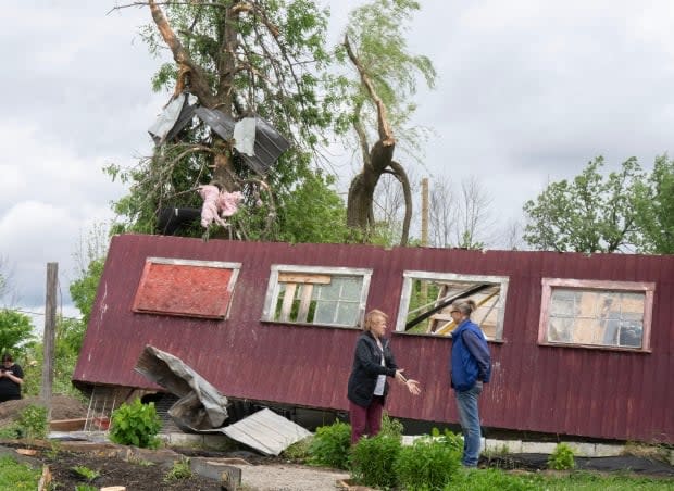 Julia Asselstine, right, surveys the damage to her property in Tres-Saint-Redempteur, Que. after a tornado touched down on May 28.