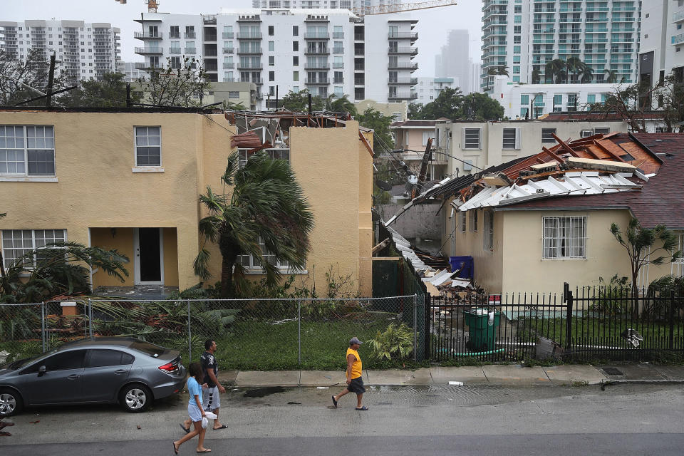 MIAMI, FL - SEPTEMBER 10:  People walk past a building where the roof was blown off by Hurricane Irma on September 10, 2017 in Miami, Florida. Hurricane Irma, which first made landfall in the Florida Keys as a Category 4 storm on Sunday, has weakened to a Category 2 as it moves up the coast.  (Photo by Joe Raedle/Getty Images)