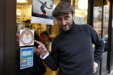 Stephan Martinez, owner of Le Petit Choiseuil bistrot, points at a sticker for a pilot project to collect food waste in Paris February 12, 2014. REUTERS/Charles Platiau