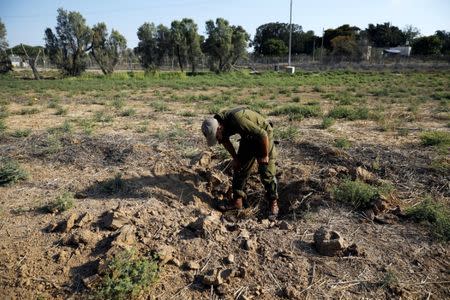 An Israeli soldier inspects a place where a rocket fell near the Israeli Kibbutz of Nachal Oz, on the Israeli side of the Israel - Gaza border July 14, 2018 REUTERS/Amir Cohen