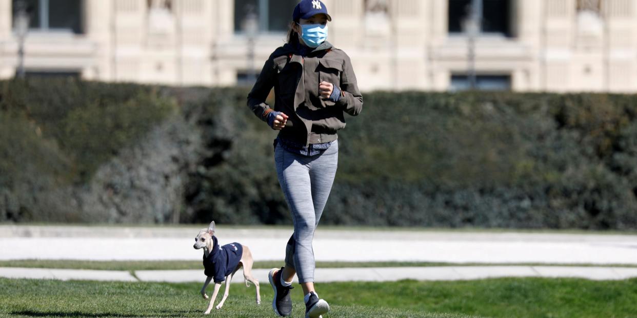 FILE PHOTO: A lone jogger, wearing a protective face mask, runs with her dog in the Tuileries Garden in Paris as a lockdown is imposed to slow the rate of the coronavirus disease (COVID-19) spread in France, March 23, 2020. REUTERS/Charles Platiau/File Photo