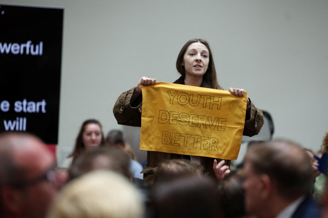 A woman holds a banner at the launch of the Labour Party's manifesto, in Manchester, Britain, June 13, 2024. REUTERS/Phil Noble