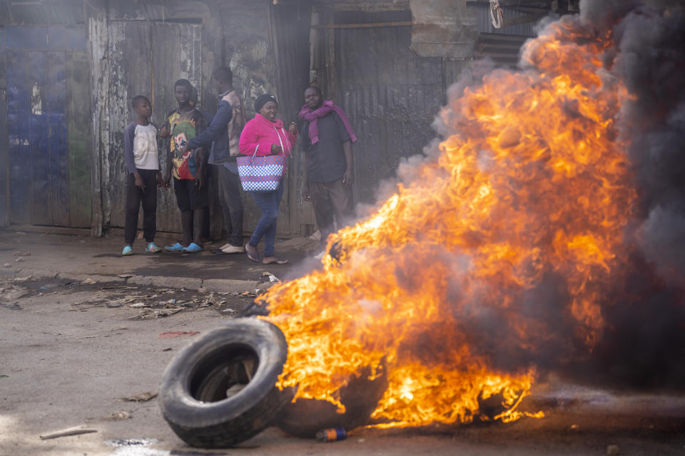 A passerby walks next to a burning barricade in the Kibera slum of Nairobi, Kenya Monday, March 20, 2023. Hundreds of opposition supporters have taken to the streets of the Kenyan capital over the result of the last election and the rising cost of living, in protests organized by the opposition demanding that the president resigns from office. (AP Photo/Ben Curtis)