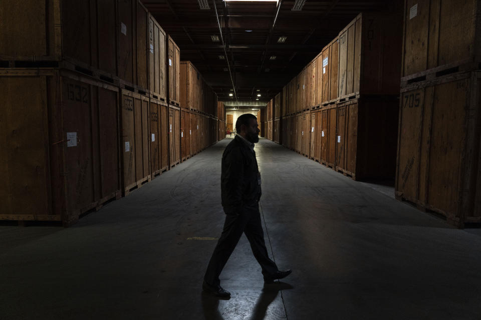 Henry Agadjanyan, operations chief for the Los Angeles County Public Administrator, a branch of the county's Department of the Treasurer and Tax Collector, walks past the rows of double-stacked wooden crates at a county warehouse in the County of Los Angeles, Calif., Thursday, June 15, 2023. The crates are filled with belongings from people's estates. The items will be auctioned off to the public to pay off the estates' debts and burial or cremation services. (AP Photo/Jae C. Hong)